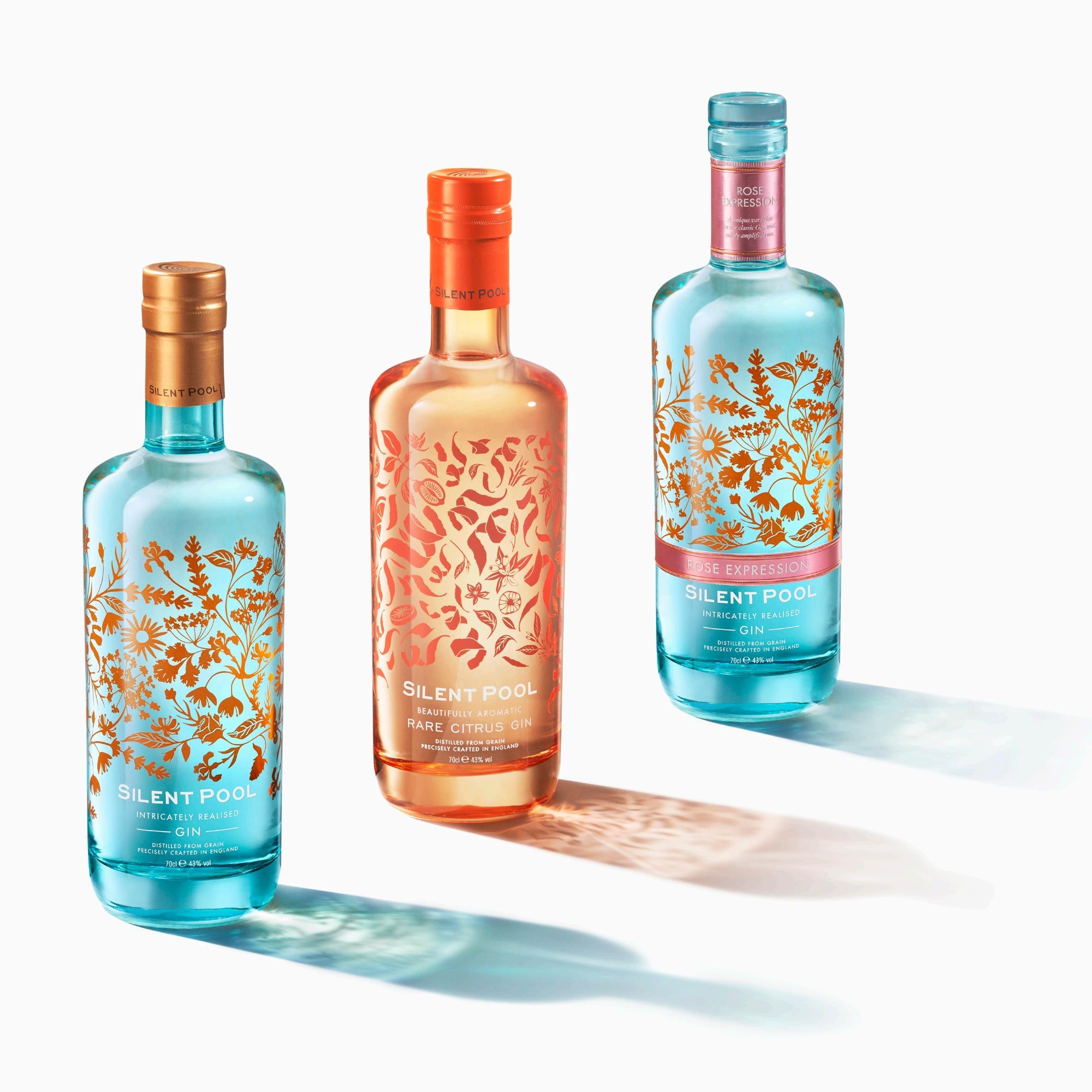 Three bottles of Silent River gin with floral designs on a white background