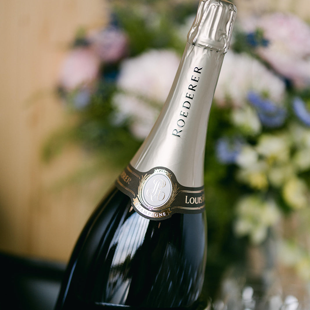 Bottle of Roederer champagne in an ice bucket with flowers in the background
